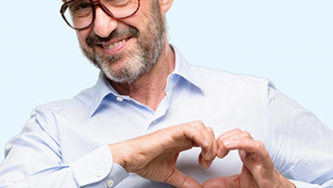 smiling man making heart with hands over chest