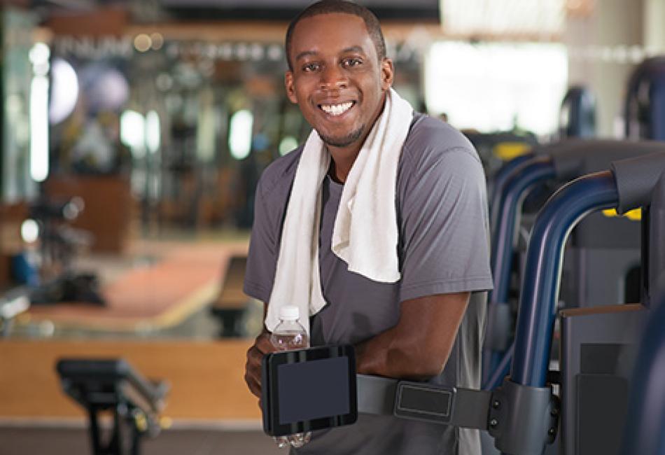 man at gym with leaning on exercise equipment smiling