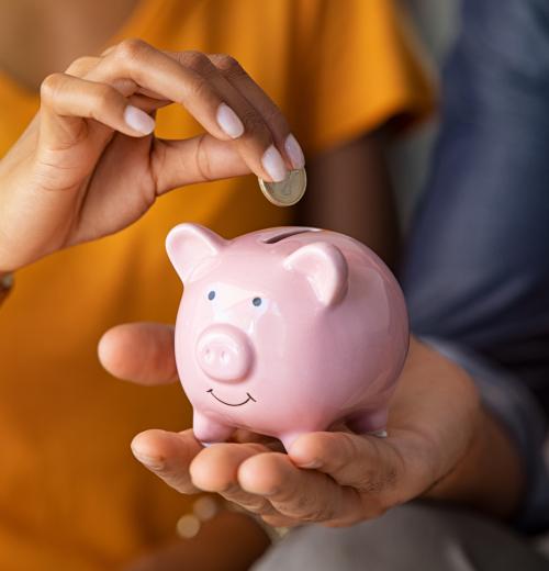 hands placing coin into piggy bank