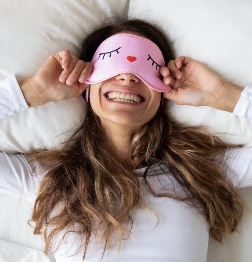 smiling woman pulling eye cover over eyes